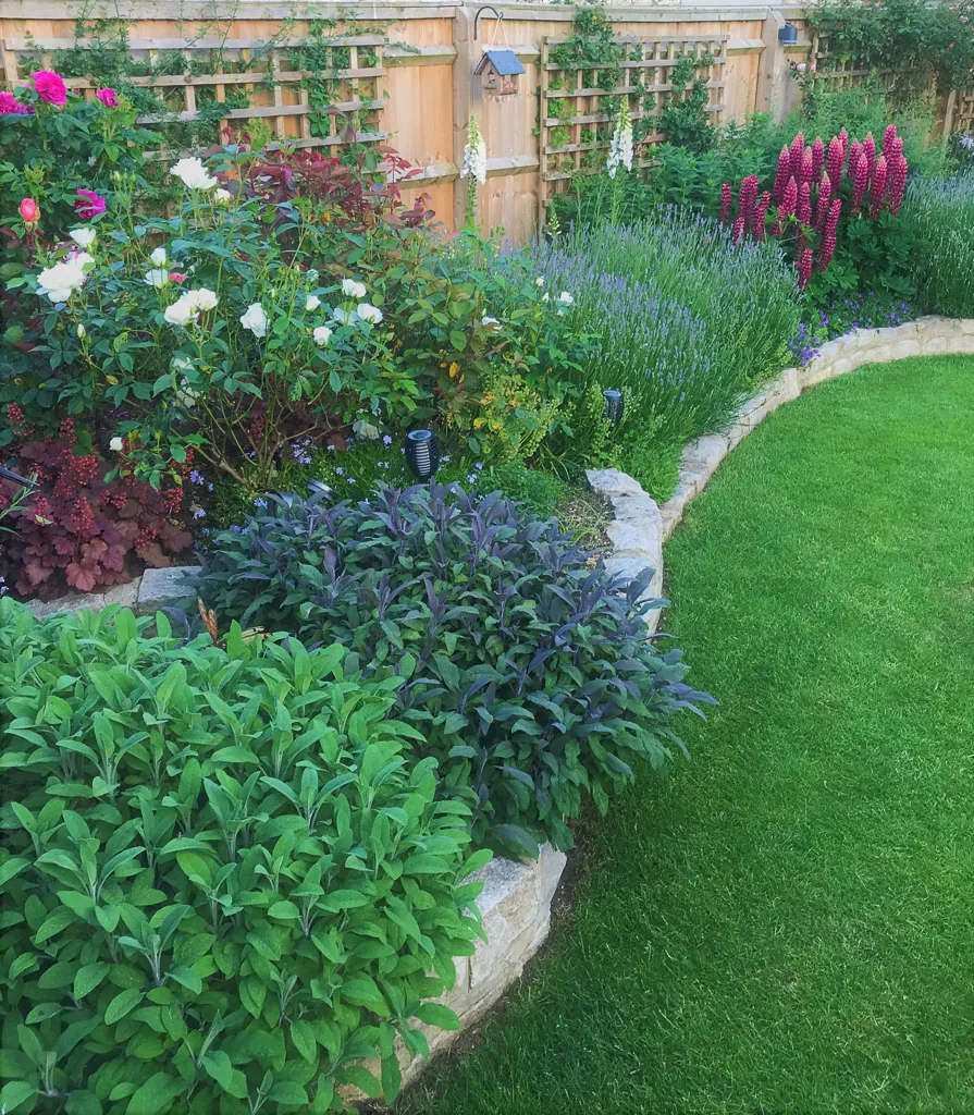 A curving stone-edged border full of flowers beside a lawn, in the Gunby garden